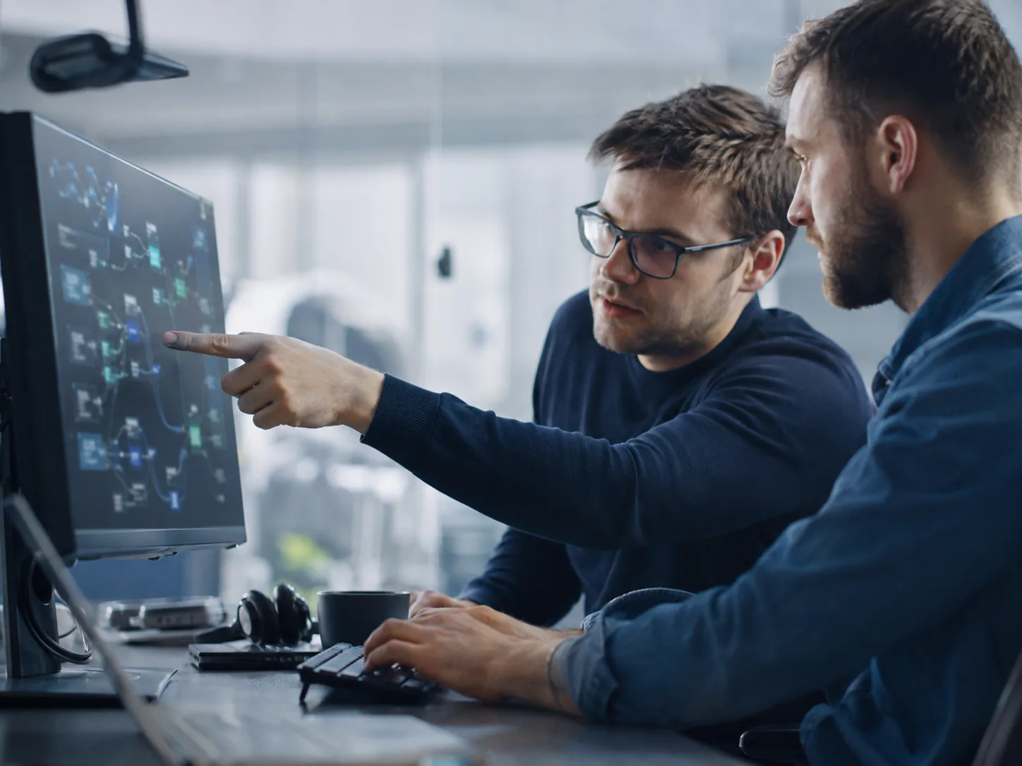 Two engineers connecting systems while reviewing a diagram on screen.