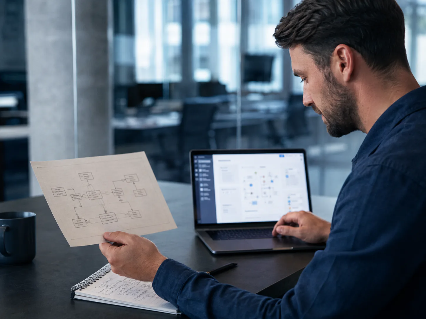 Developer comparing an existing system plan with a modern application interface.